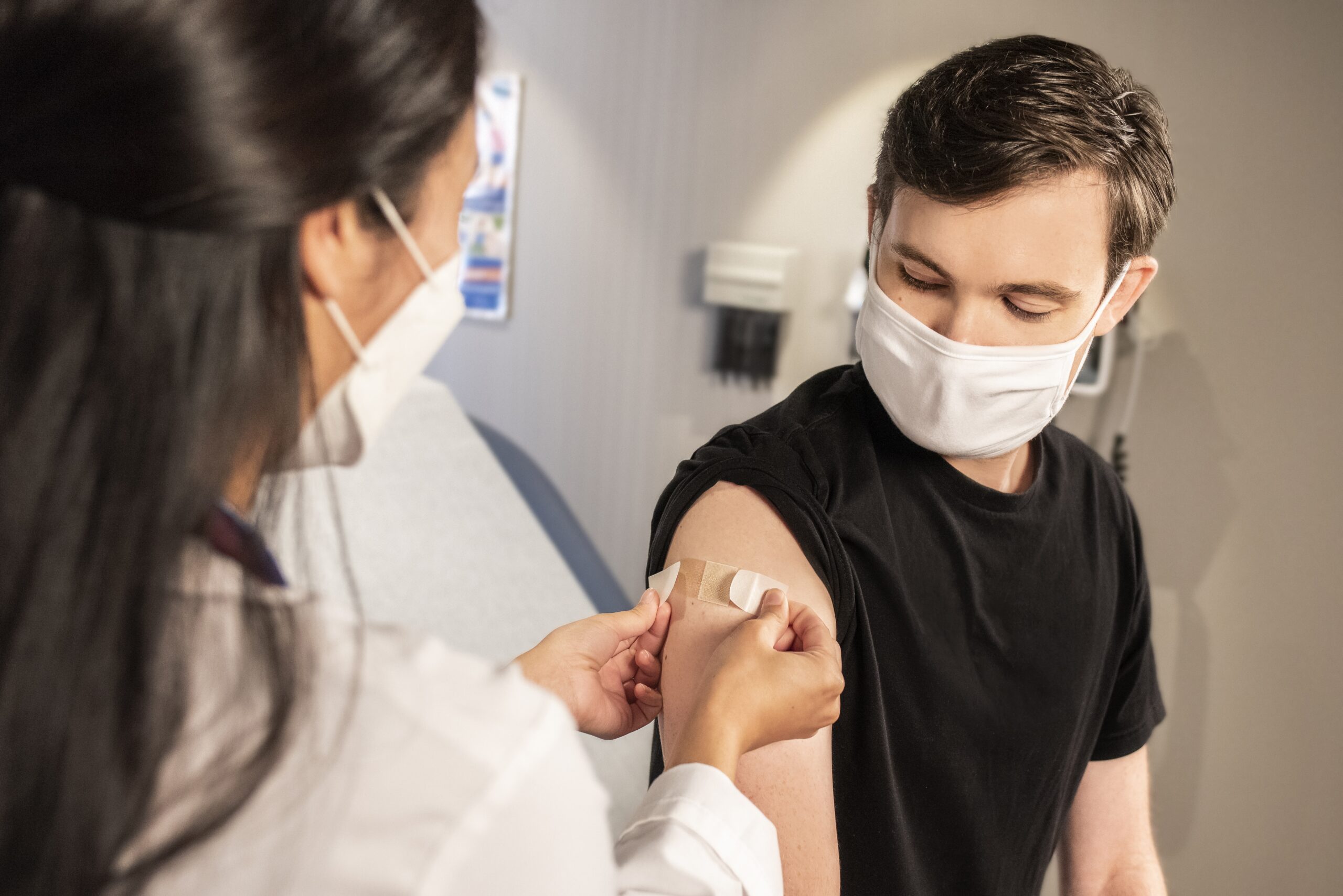 Doctor Applying Band-Aid on Young Man After Flu Shot